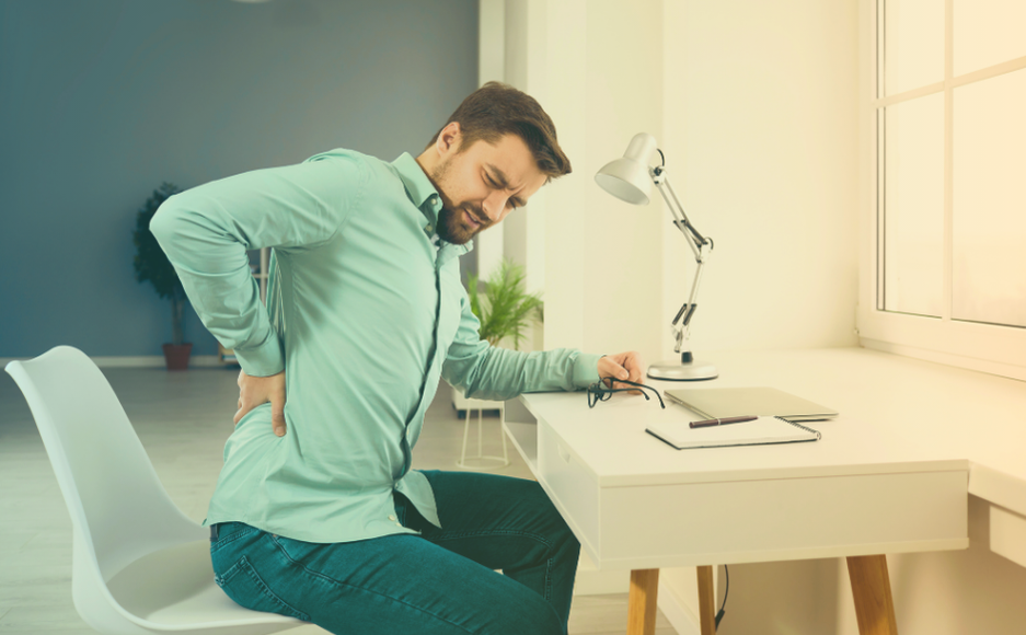 Homem sentado na cadeira sentindo dor na lombar.