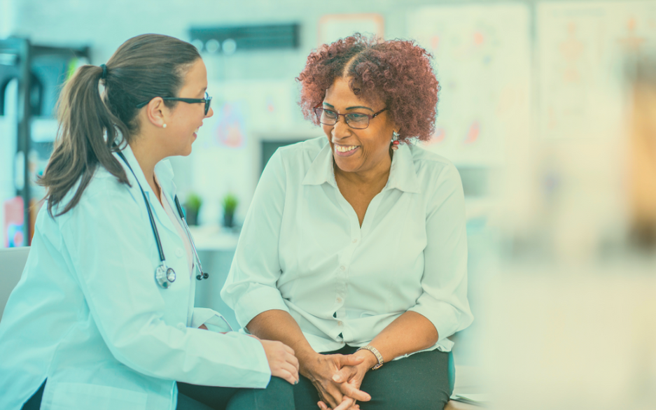 Médica e paciente sorrindo enquanto conversam.