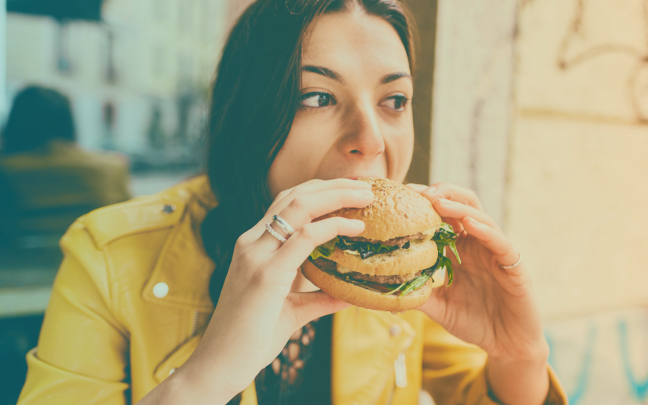 Mulher comendo hambúrguer.