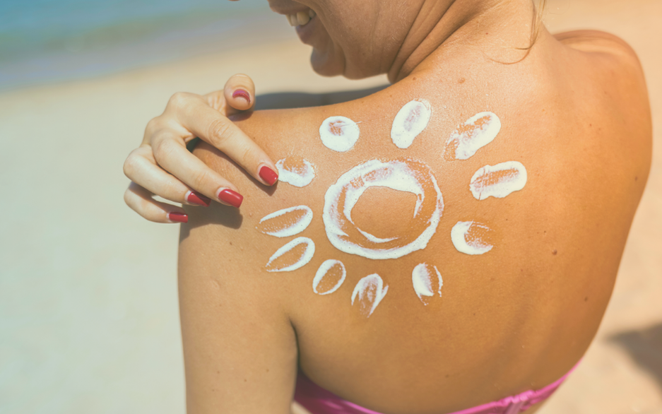 Mulher desenhando um sol com protetor solar nas costas.