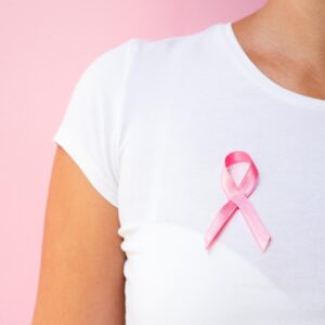 Mulher com laço rosa preso na blusa, símbolo da campanha Outubro Rosa.