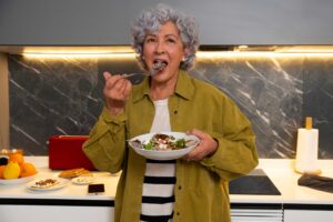 Mulher idosa se alimentando de forma saudável em casa, representando reeducação alimentar, nutrição equilibrada e cuidado com a saúde na terceira idade com apoio do Cartão Benefícios Ágape Sênior